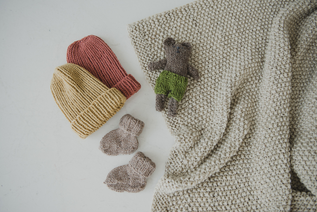 Yellow and Orange Knitted Beanies on White Surface 